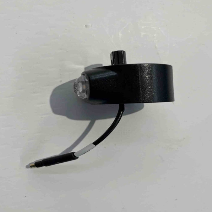 The Go2place-okai-parts ES600P front turn signal left features a sleek black cylindrical electronic design with a cable, jack plug, and a protruding sensor. It rests on a light gray surface, casting a subtle shadow.