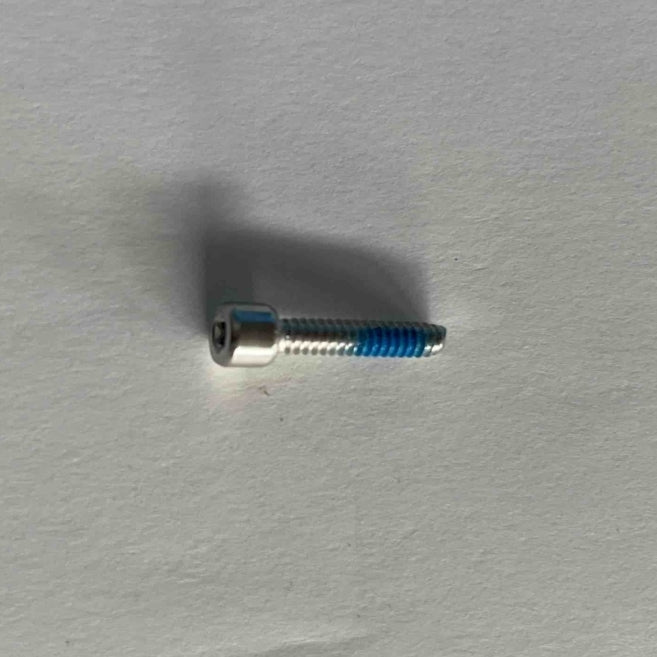 An ES600P cylindrical head torx screw with column from Go2place-okai-parts, part number 2040100942, gracefully rests on a white surface, enhanced by the play of light and shadow.