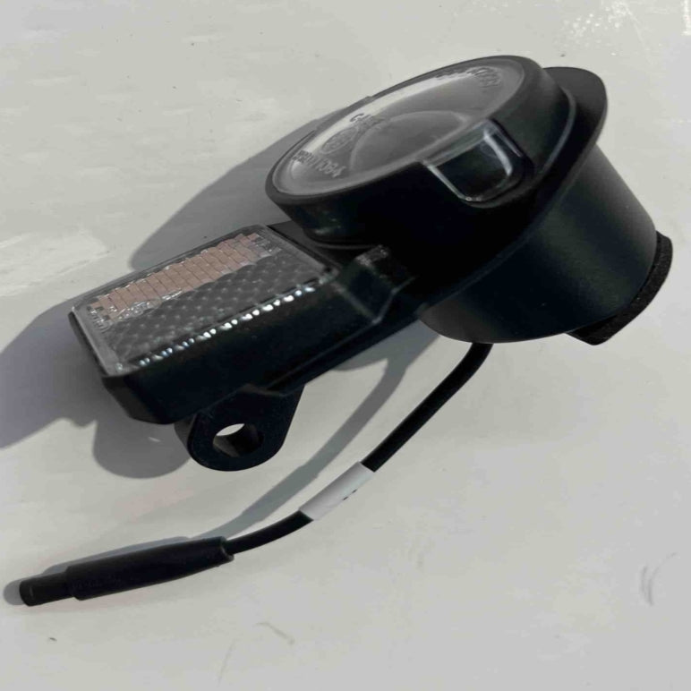 The black ES600P headlight by Go2place-okai-parts, part number 2011000232, features a round lens and rectangular component resting on white. It includes a connected cable with a small plug at the end.