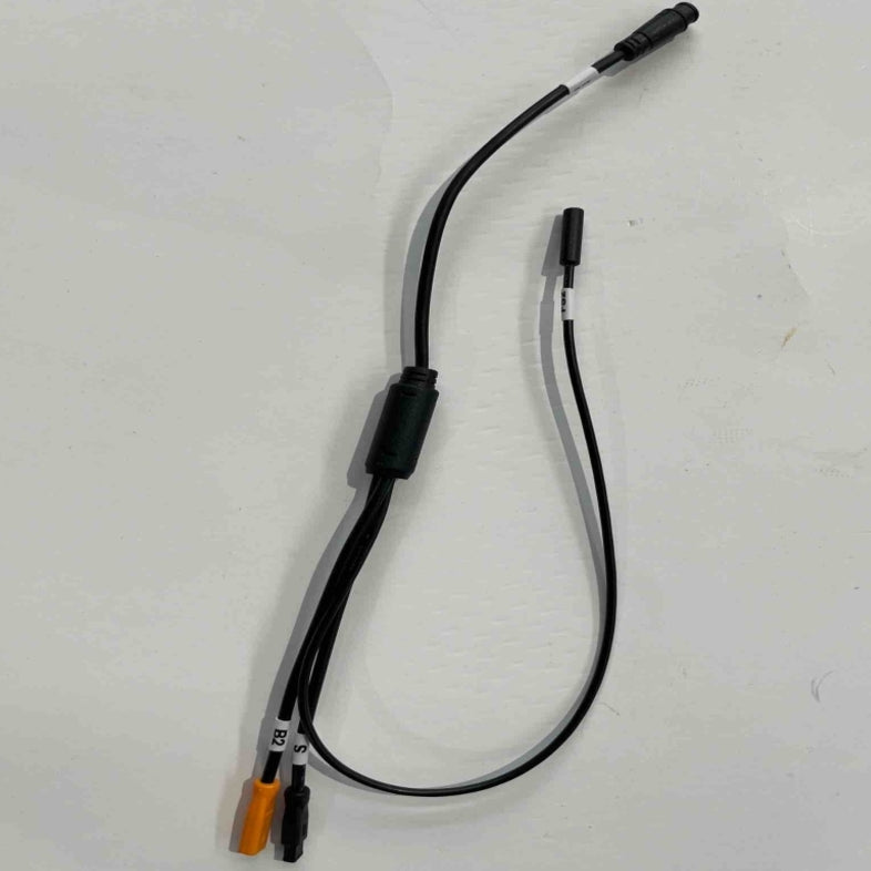 The Go2place-okai-parts ES600P adapter cable, featuring a black design with multiple connectors, lies on a plain white surface. One end has a thicker connector, while the other splits into orange and black connectors. The main section includes a small bulky component labeled 2011300690.
