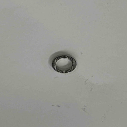 An EB100B anti-loosening gasket, part number 2040500097 from Go2place-okai-parts, is mounted on a white ceiling with a circular grill pattern around its edge and faint marks nearby.
